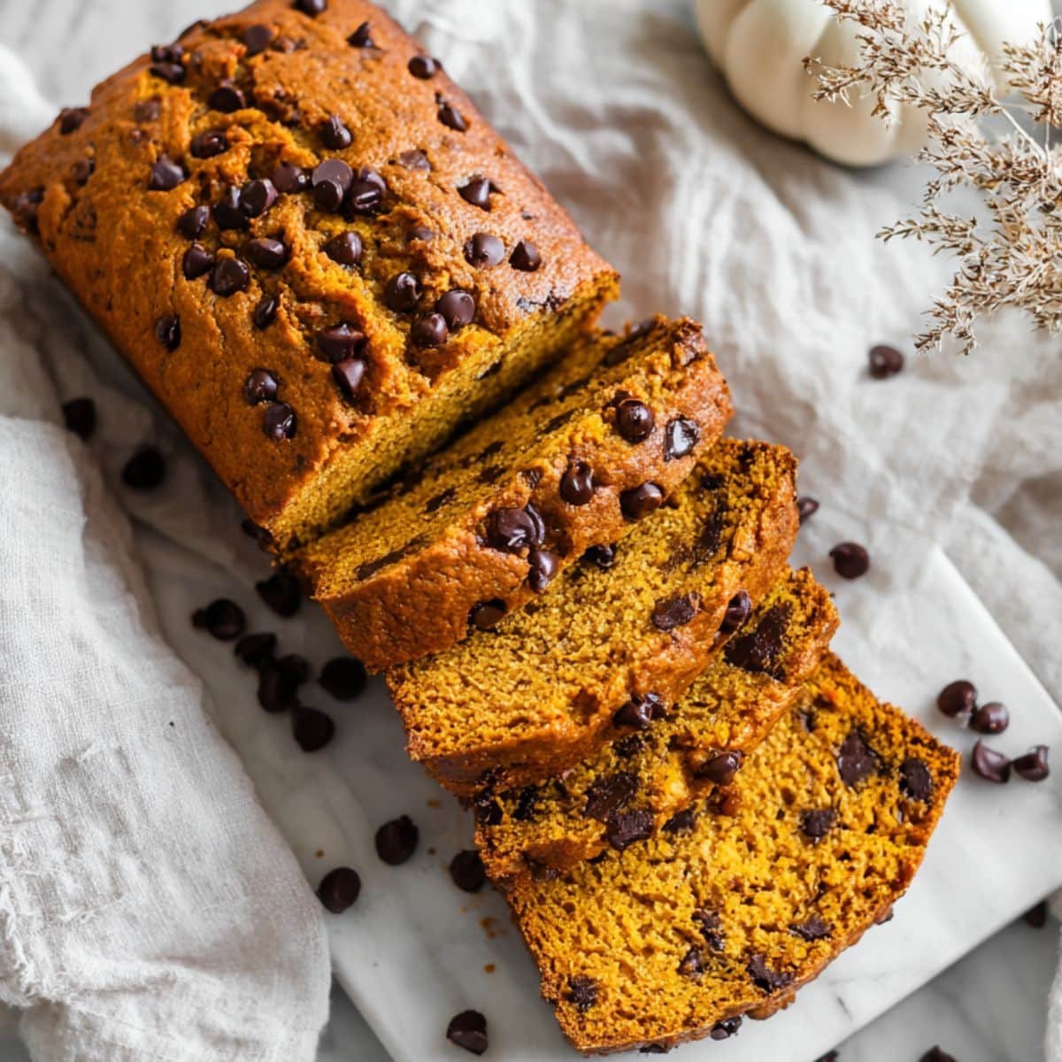 Sliced pumpkin chocolate chip bread with melty chips on marble top