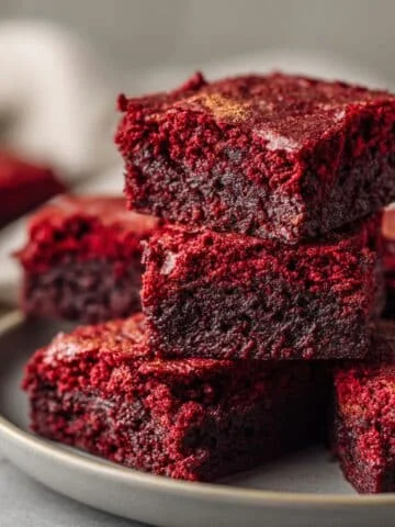 Top-down photo of homemade red velvet brownies cut into squares on white plate