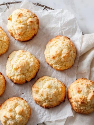 Freshly baked sour cream cookies cooling on parchment paper in a white kitchen