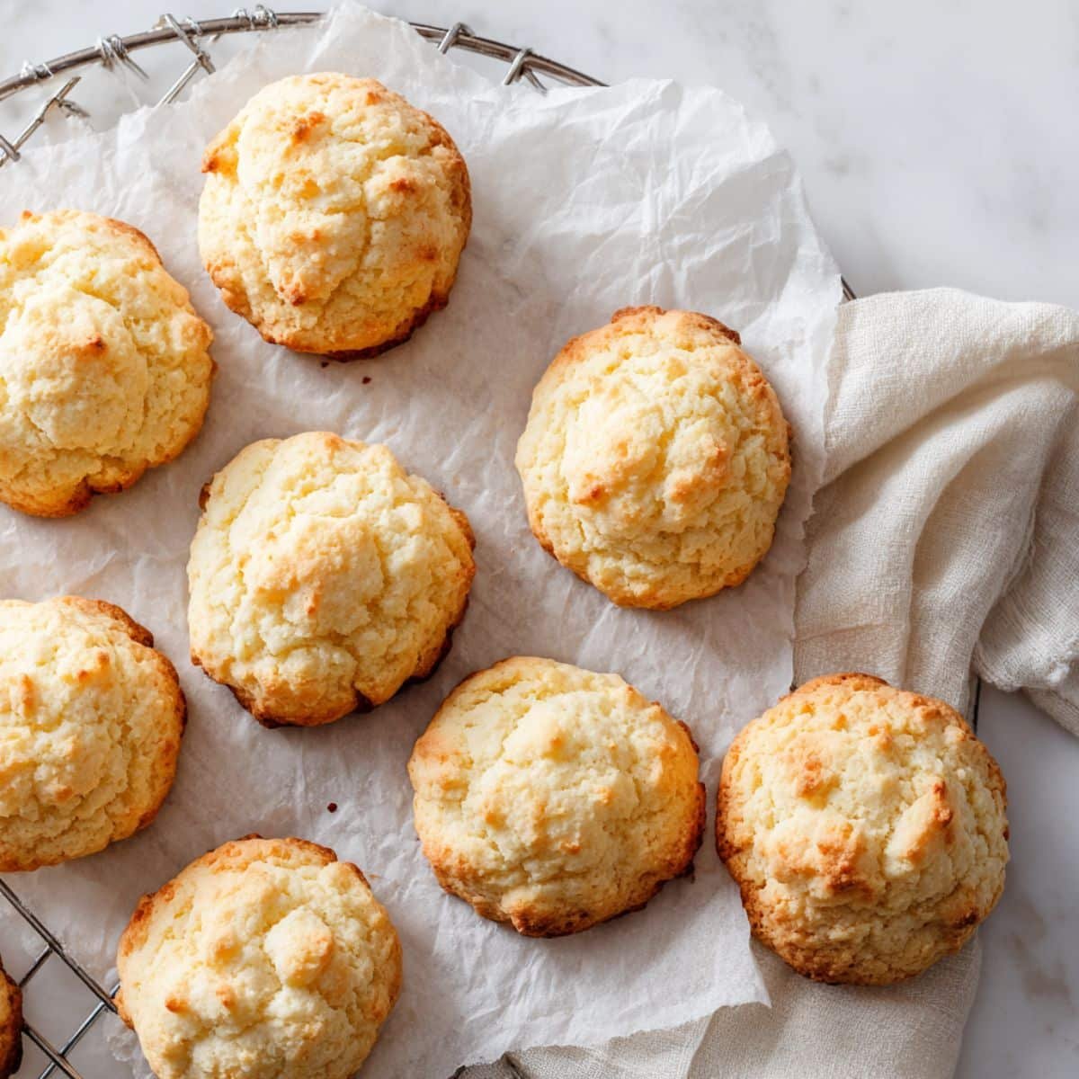 Freshly baked sour cream cookies cooling on parchment paper in a white kitchen