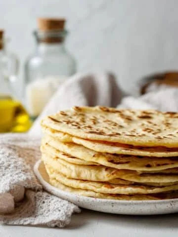 Stack of homemade unleavened bread on white counter in bright kitchen