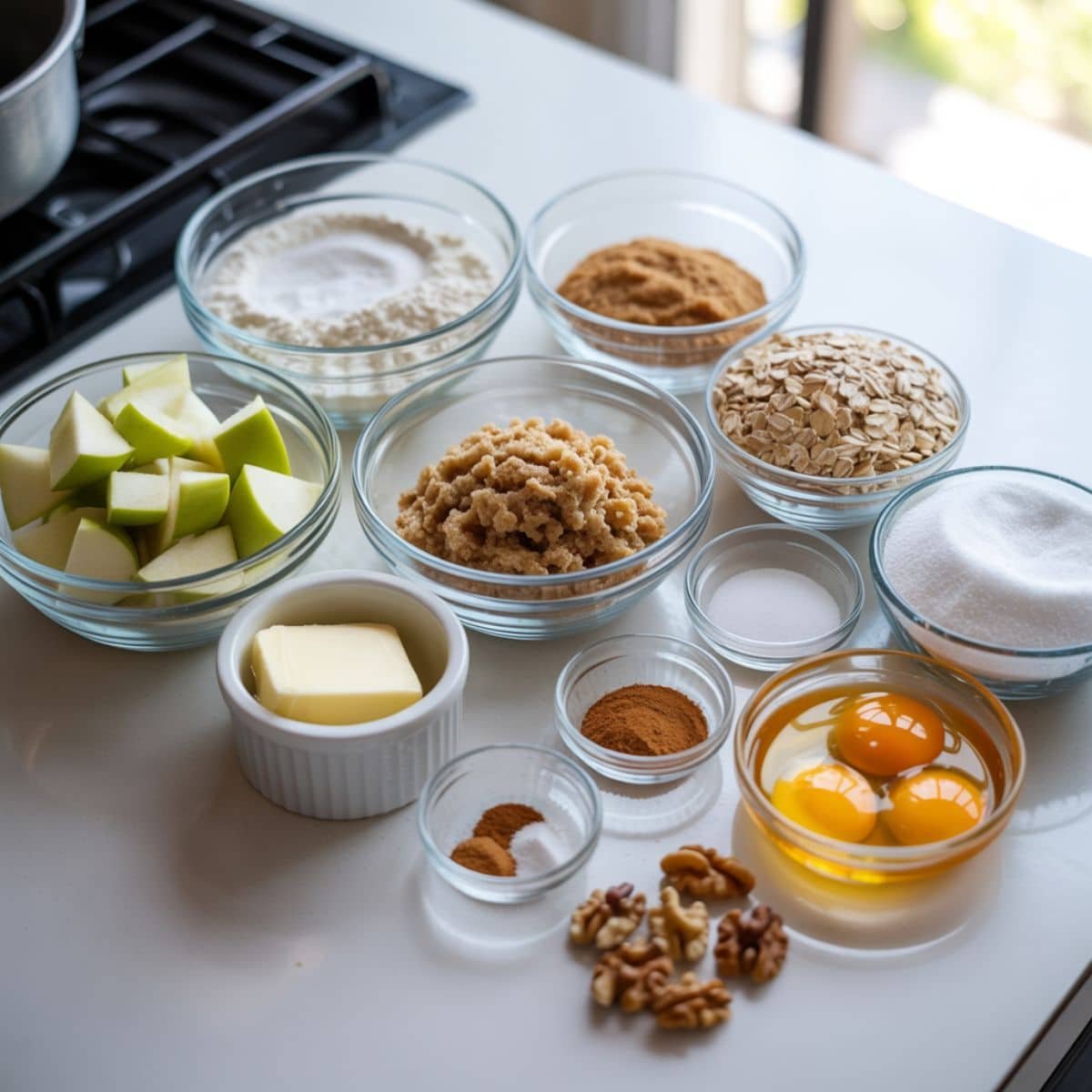 Flat lay of Apple Cookies ingredients measured out on a white kitchen table, including apples, flour, oats, sugars, butter, eggs, and spices.