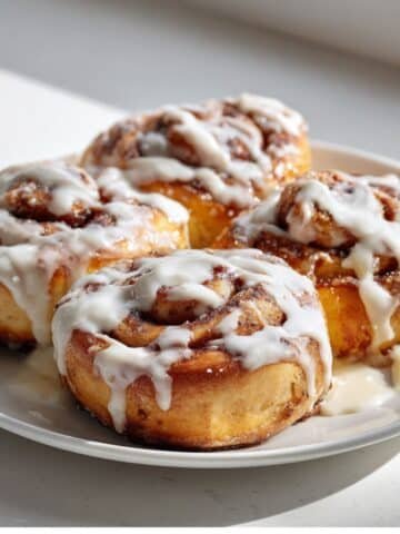 Fresh Cinnamon Roll Icing on a white kitchen table, photographed from above.