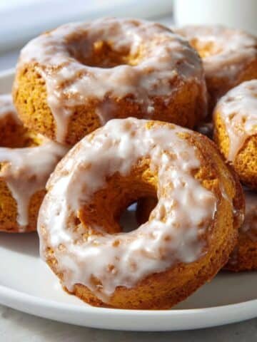 homemade baked pumpkin donuts on a white kitchen table, light maple glaze with a few