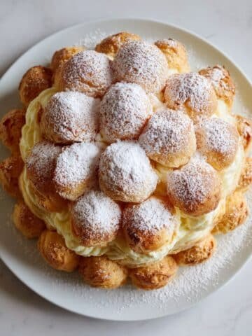 homemade cream puff cake on a white kitchen table, dusted with powdered sugar