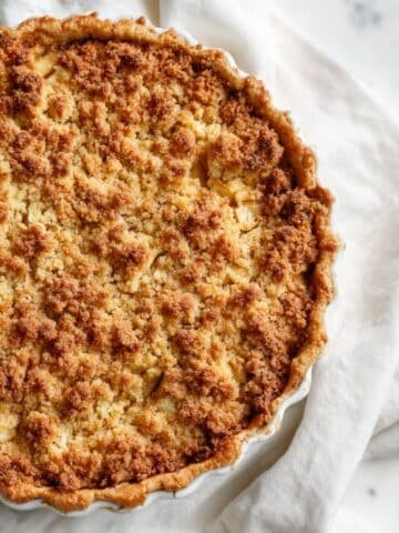 Freshly baked Dutch apple pie with golden buttery streusel topping on a white kitchen counter, top-down view