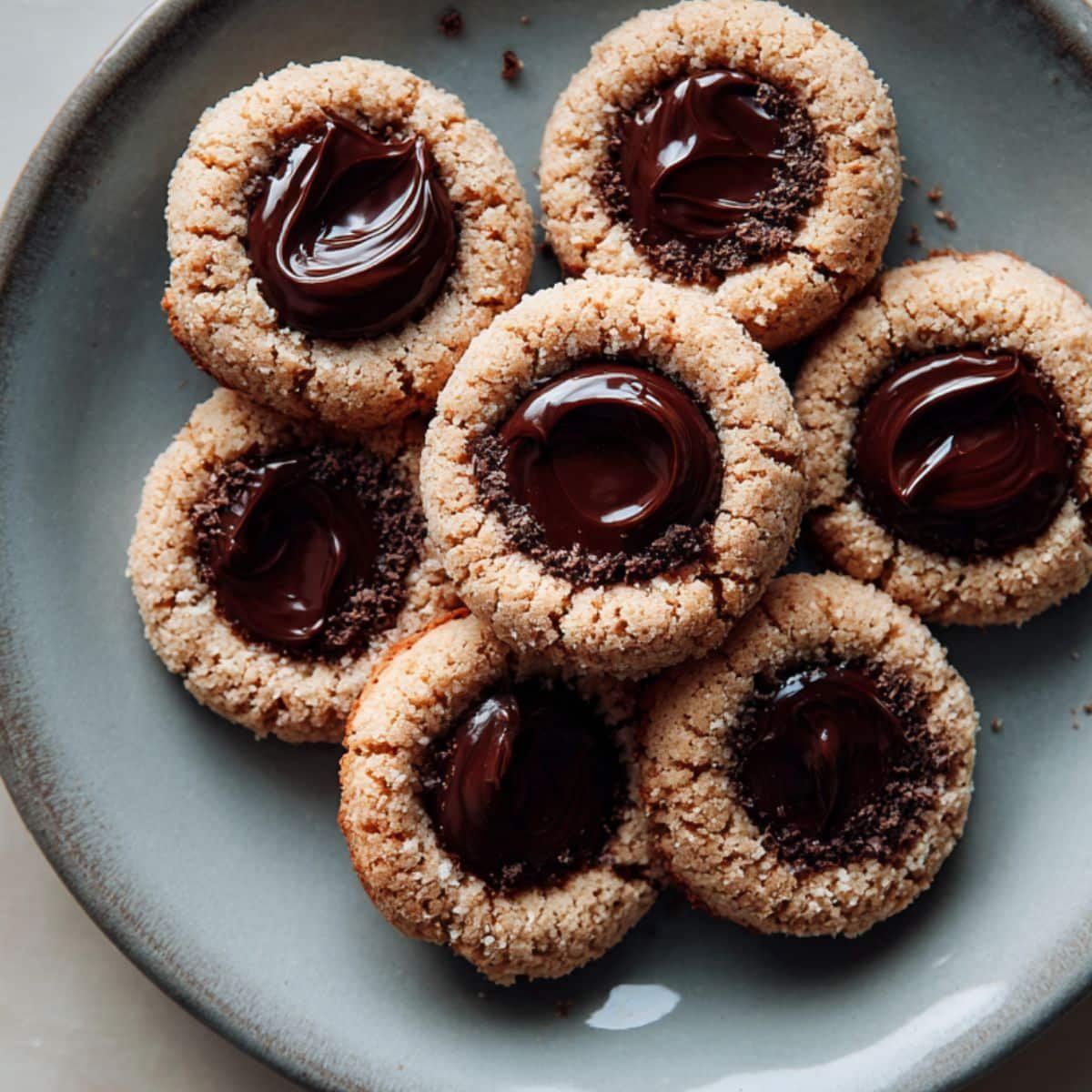 Top-down tray of  thumbprint cookies chocolate with ganache on a white table.