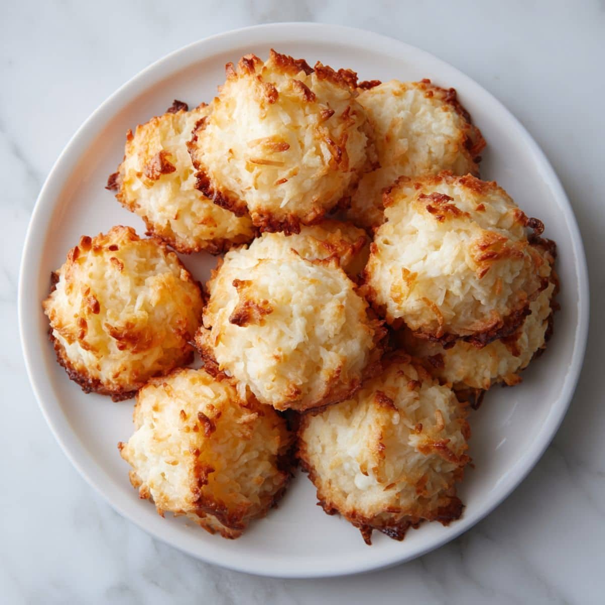 Homemade Gluten Free Macaroons cooling on parchment paper, photographed from above on a white kitchen counter.