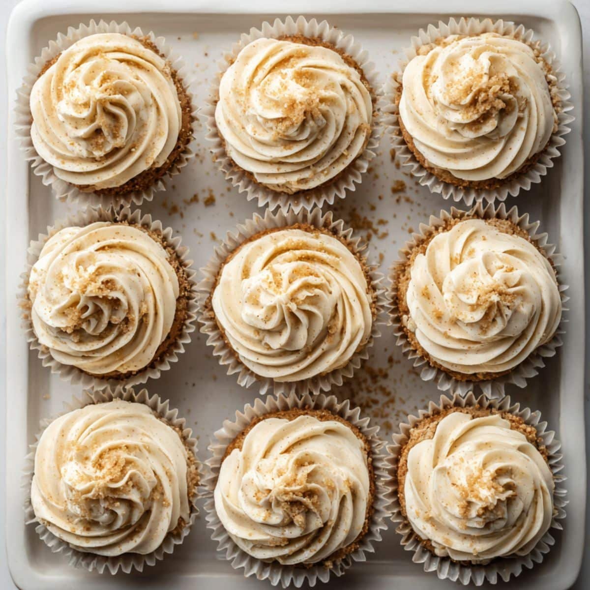 Freshly baked vegan cupcake recipe with swirled frosting on a white kitchen table, captured in natural light.