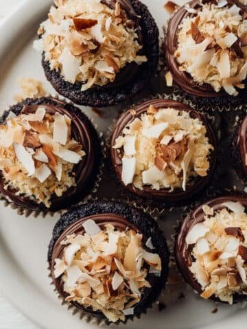 Homemade almond joy cupcakes with coconut filling, topped with ganache, almonds, and coconut flakes
