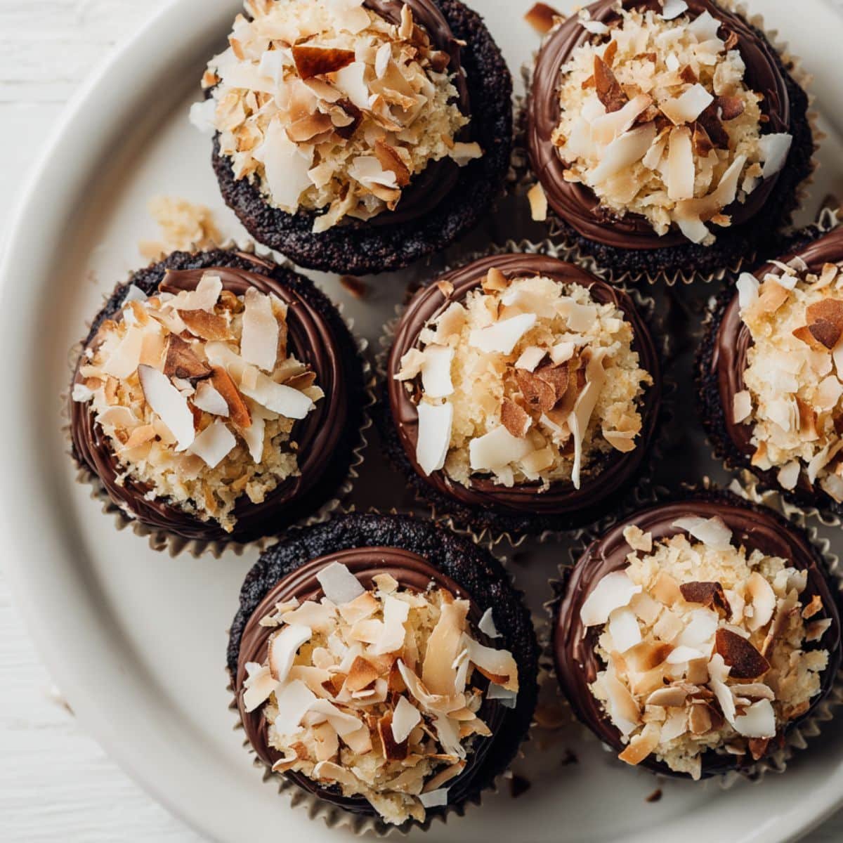 Homemade almond joy cupcakes with coconut filling, topped with ganache, almonds, and coconut flakes