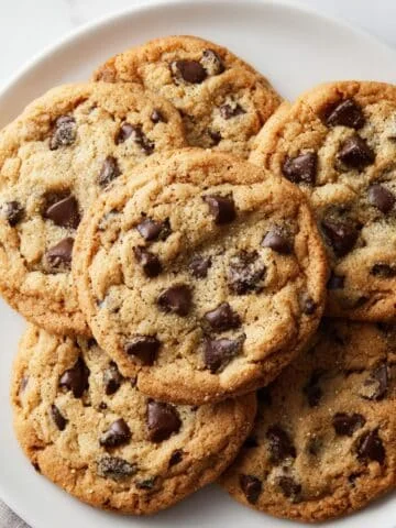 Freshly baked chewy brown sugar chocolate chip cookies on plate, shot from above on a white kitchen table