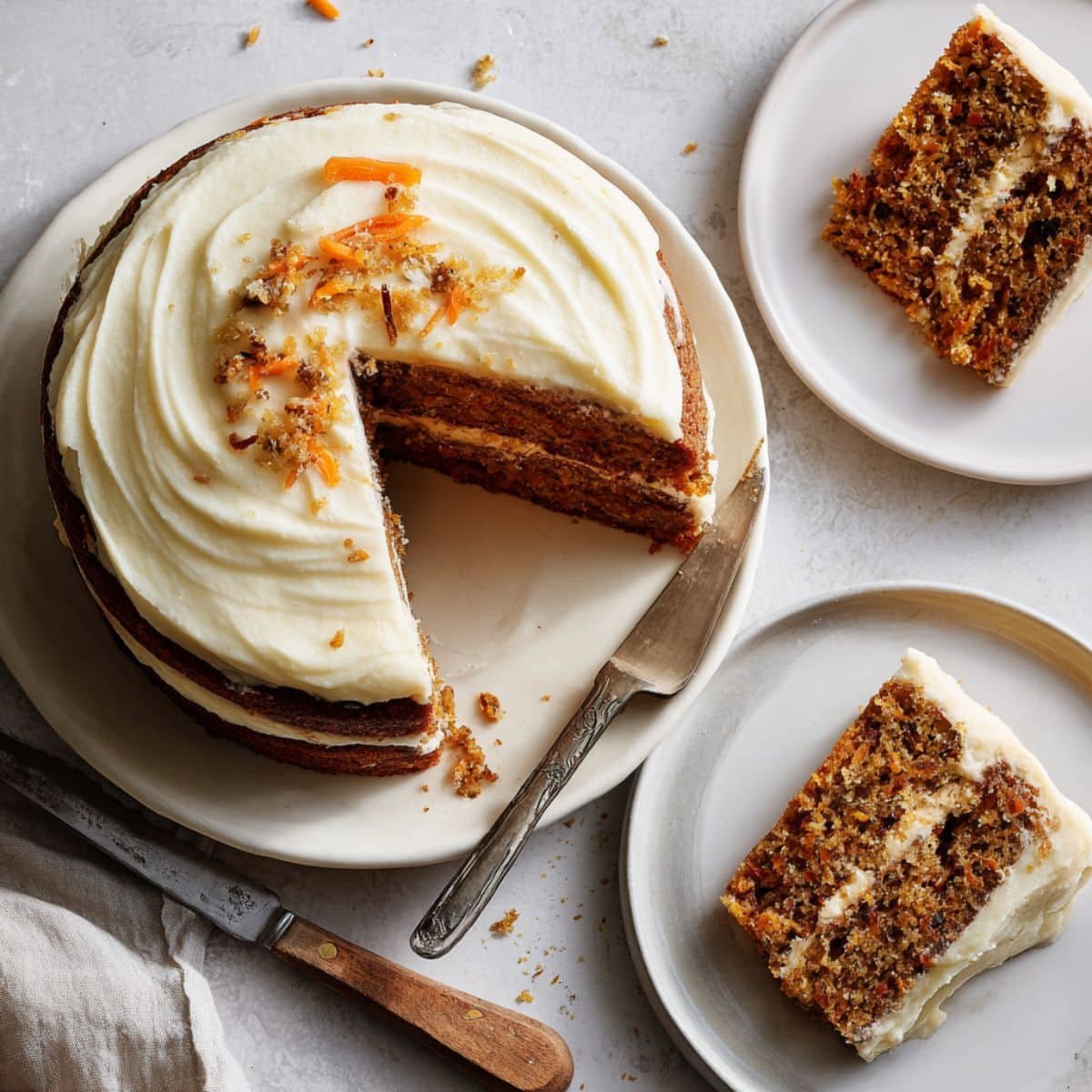 Homemade carrot and cheesecake cake with cream cheese frosting on a white kitchen counter, top-down view