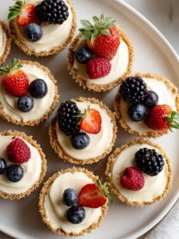 Top-down view of creamy cheesecake cupcakes recipe with graham cracker crust and berry topping in a white kitchen