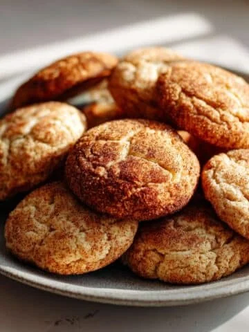Soft and chewy cinnamon cookies cooling on a wire rack with milk on a white kitchen counter