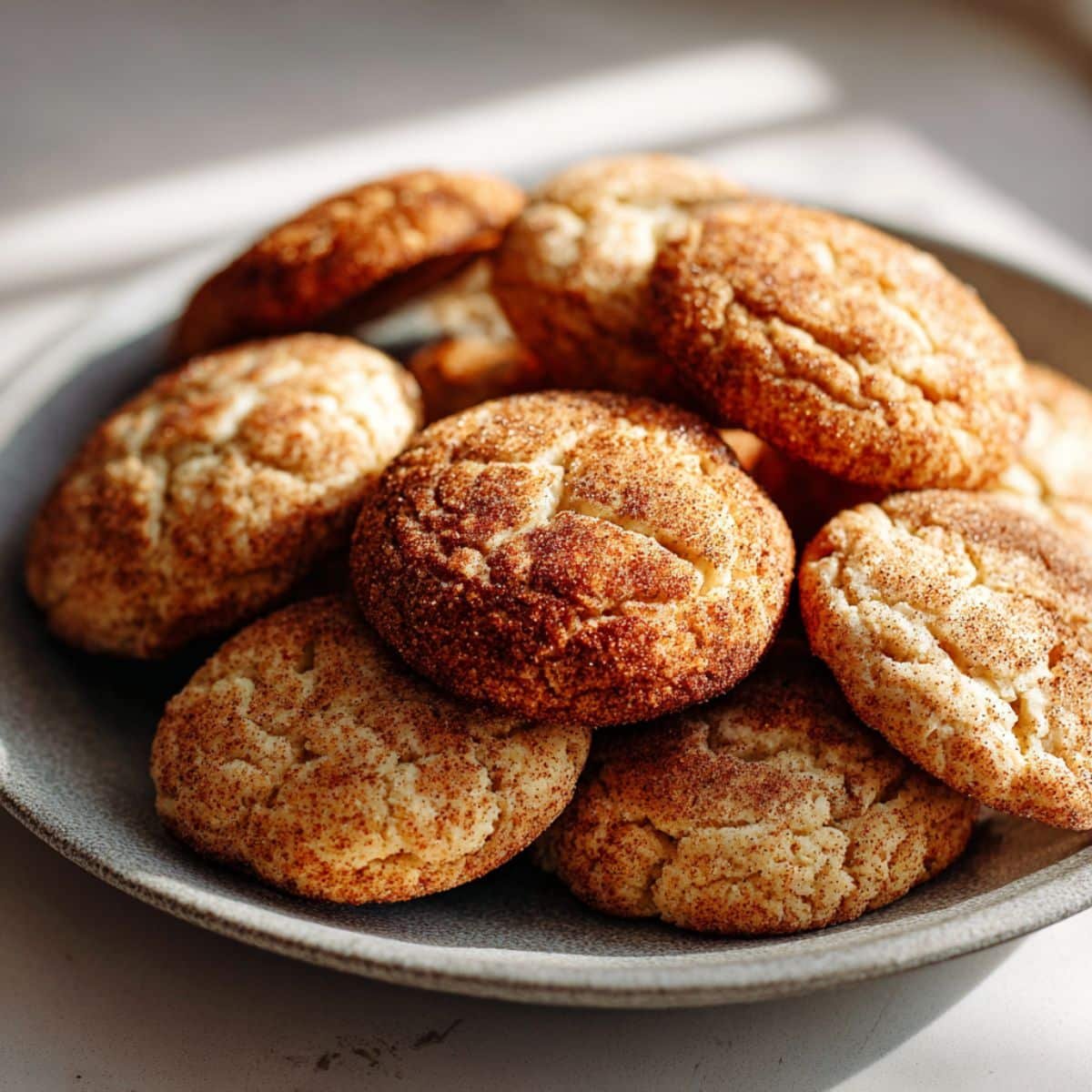 Soft and chewy cinnamon cookies cooling on a wire rack with milk on a white kitchen counter