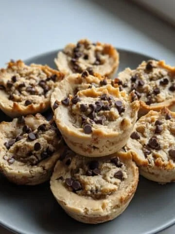 Homemade cookie dough cups on a white kitchen table, rustic and imperfect with chocolate chips and peanut butter filling, shot from above