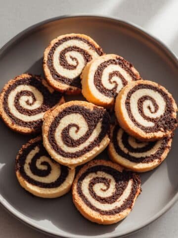 A batch of homemade chocolate pinwheel cookies with chocolate and vanilla swirls on a white kitchen table, photographed from above.