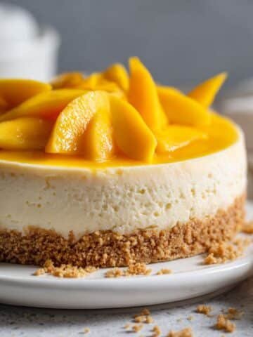 Homemade no bake mango cheesecake on a white kitchen table, topped with fresh mango slices, rustic and realistic presentation.