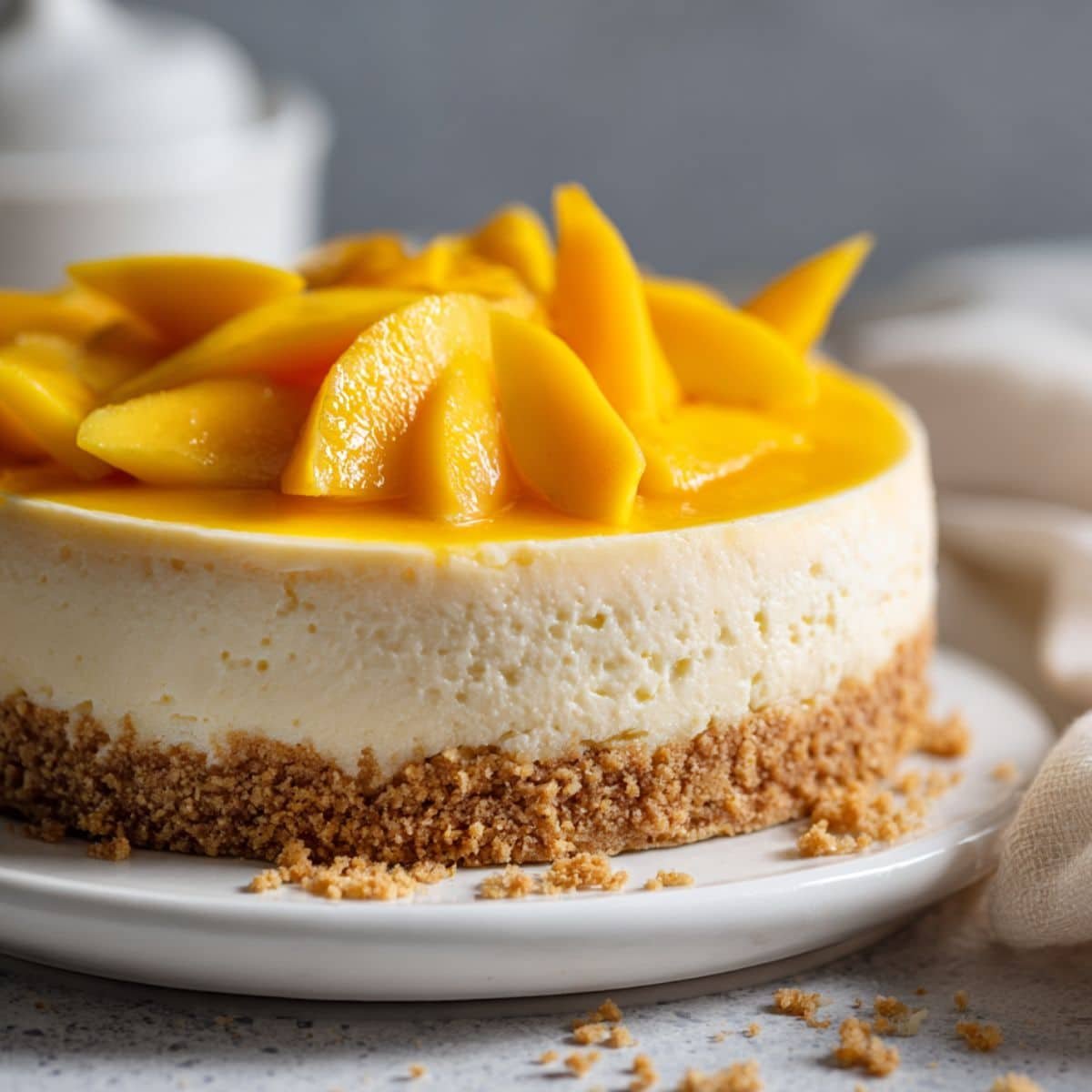 Homemade no bake mango cheesecake on a white kitchen table, topped with fresh mango slices, rustic and realistic presentation.