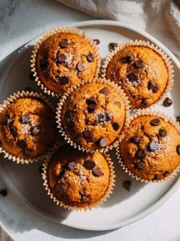 Flourless pumpkin muffins on a white kitchen counter with chocolate chips
