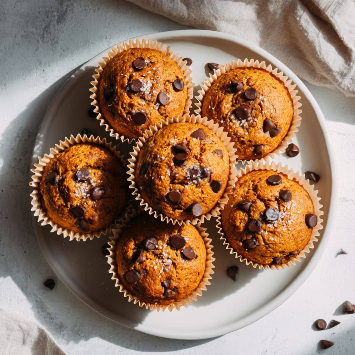Flourless Pumpkin Muffins on a white kitchen counter with chocolate chips