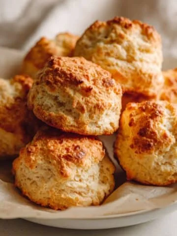 Fluffy homemade gluten free biscuits on parchment paper, baked golden brown on a white kitchen counter.