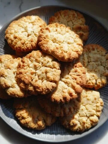Freshly baked homemade maple cookies on a cooling rack and plate, top view on white counter.