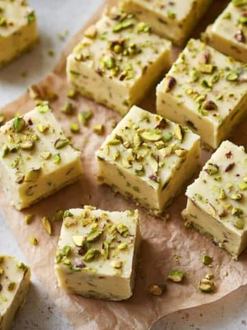 Top-down shot of pistachio fudge cut into squares on parchment paper in a white kitchen