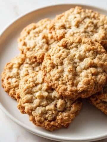 Soft and chewy oatmeal cookies with golden edges on a plate in a white kitchen