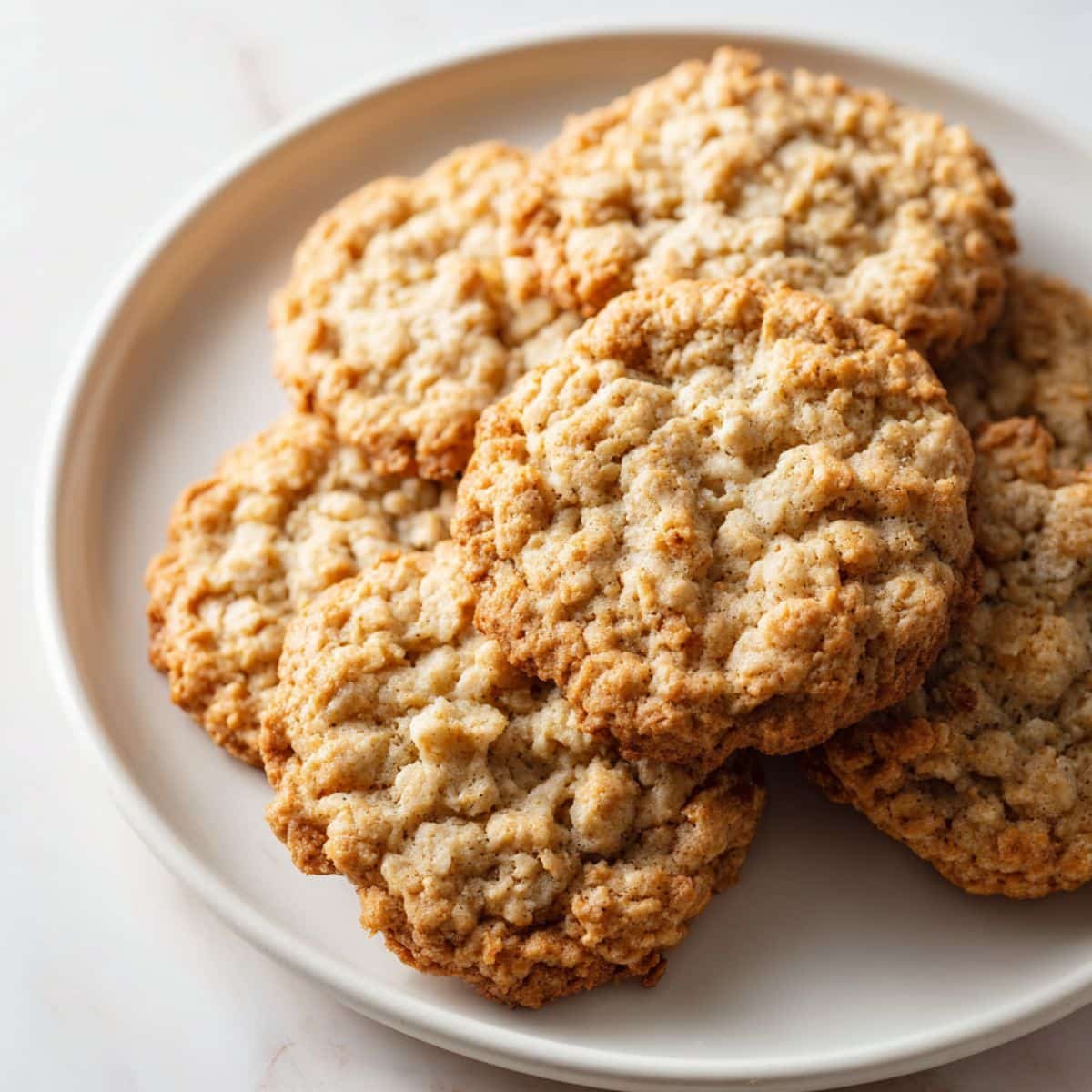 Soft and chewy oatmeal cookies with golden edges on a plate in a white kitchen