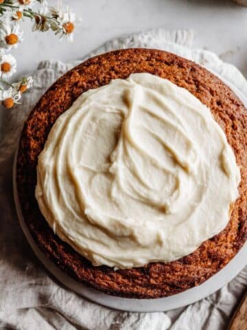 Top-down view of moist Southern sweet potato cake with cream cheese frosting on a white kitchen counter