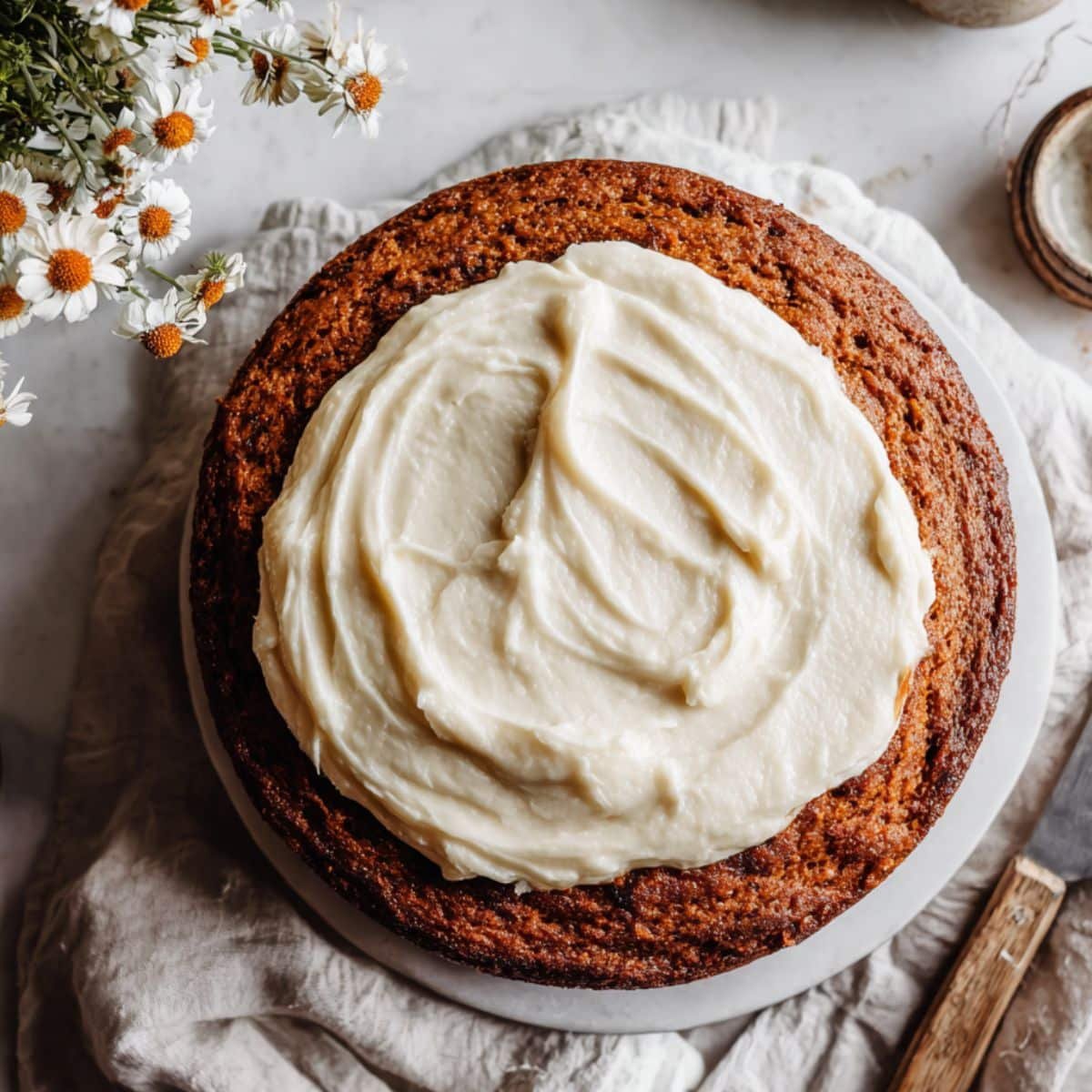 Top-down view of moist Southern sweet potato cake with cream cheese frosting on a white kitchen counter
