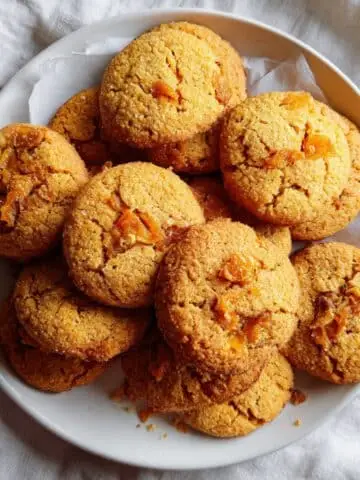 Freshly baked persimmon cookies on a white kitchen plate, golden and rustic with a homemade feel.
