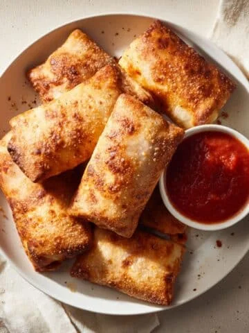 Crispy homemade Pizza Rolls in Air Fryer served with marinara sauce on a white counter