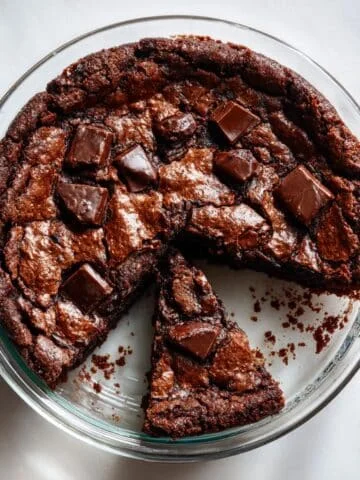 Fudgy chocolate brownie pie with a gooey center and crisp edges, shot from above on a white kitchen table in natural light.