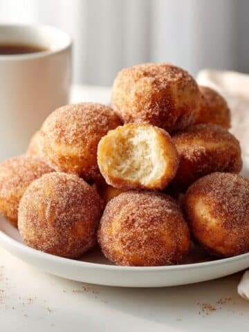 Homemade french breakfast puffs rolled in cinnamon sugar on a white kitchen table.