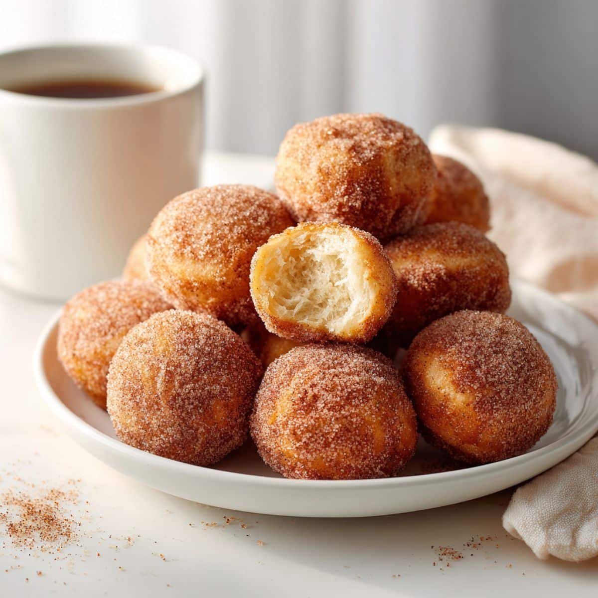 Homemade french breakfast puffs rolled in cinnamon sugar on a white kitchen table.