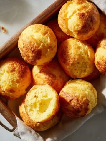 Freshly baked Brazilian cheese bread balls on a white kitchen counter, golden and slightly cracked with a homemade look.