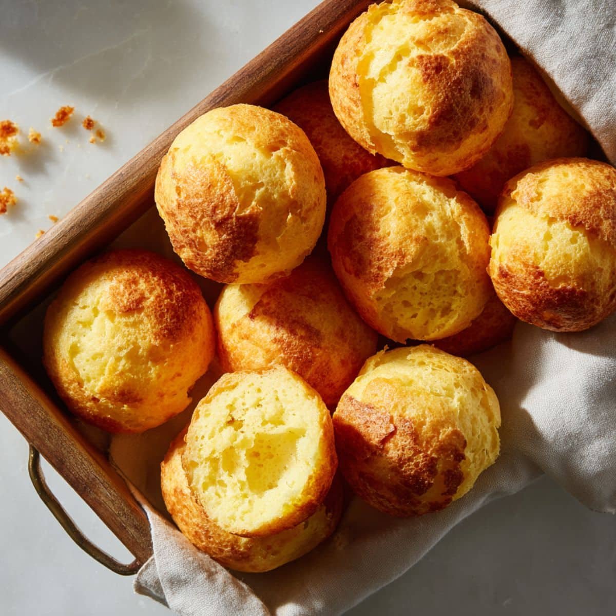 Freshly baked Brazilian cheese bread balls on a white kitchen counter, golden and slightly cracked with a homemade look.