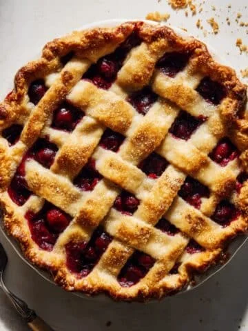 Homemade golden cherry pie on white kitchen counter, shot from above.