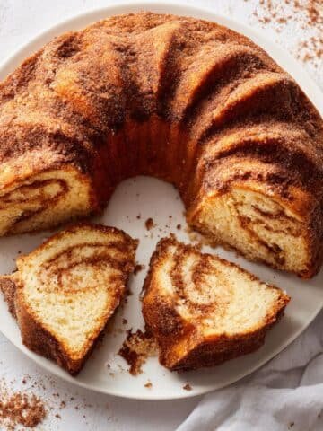Homemade churro cake with cinnamon sugar topping on a white kitchen table, top-down shot.