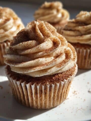 Homemade churro cupcakes with cinnamon sugar frosting on a white kitchen counter