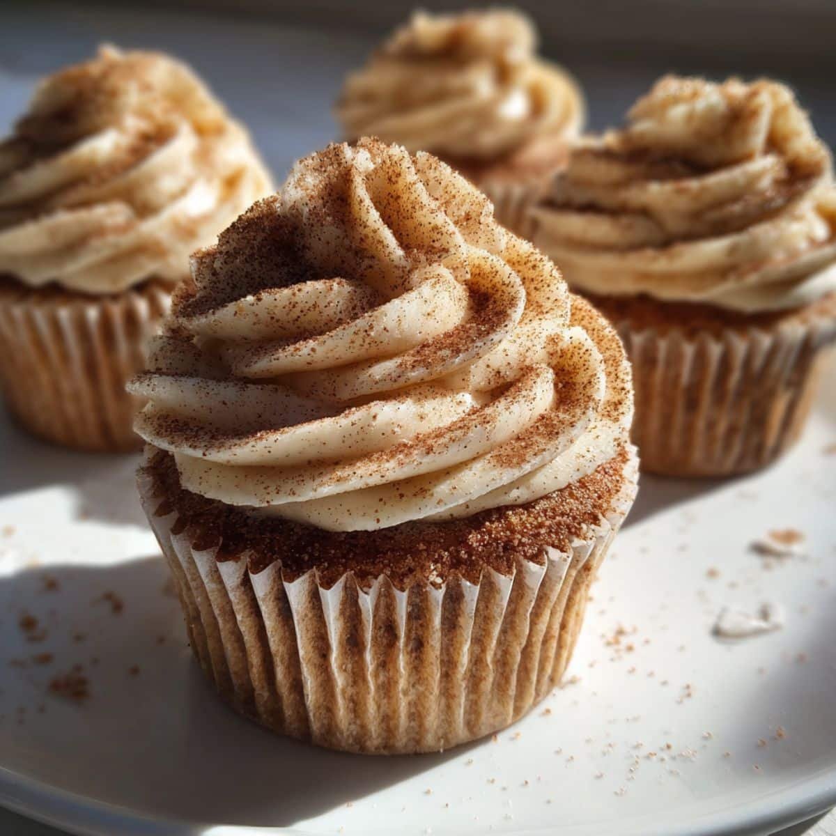 Homemade churro cupcakes with cinnamon sugar frosting on a white kitchen counter