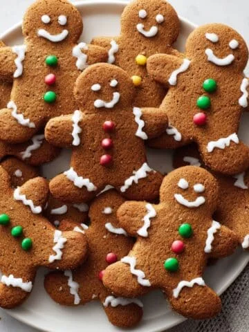 Homemade gingerbread men cookie cooling on a rack after baking, decorated with white icing and candy buttons.