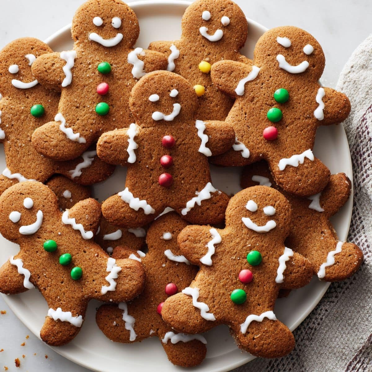 Homemade gingerbread men cookie cooling on a rack after baking, decorated with white icing and candy buttons.