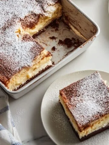 Italian Love Cake with layers of chocolate, ricotta, and pudding topping on a white kitchen table, slice removed to reveal creamy texture.