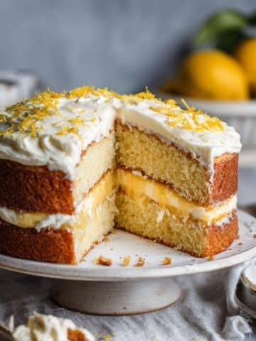 Homemade lemon curd cake slice with cream cheese frosting on a white kitchen table.