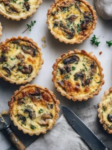 Homemade mini mushroom quiches cooling on a white kitchen table