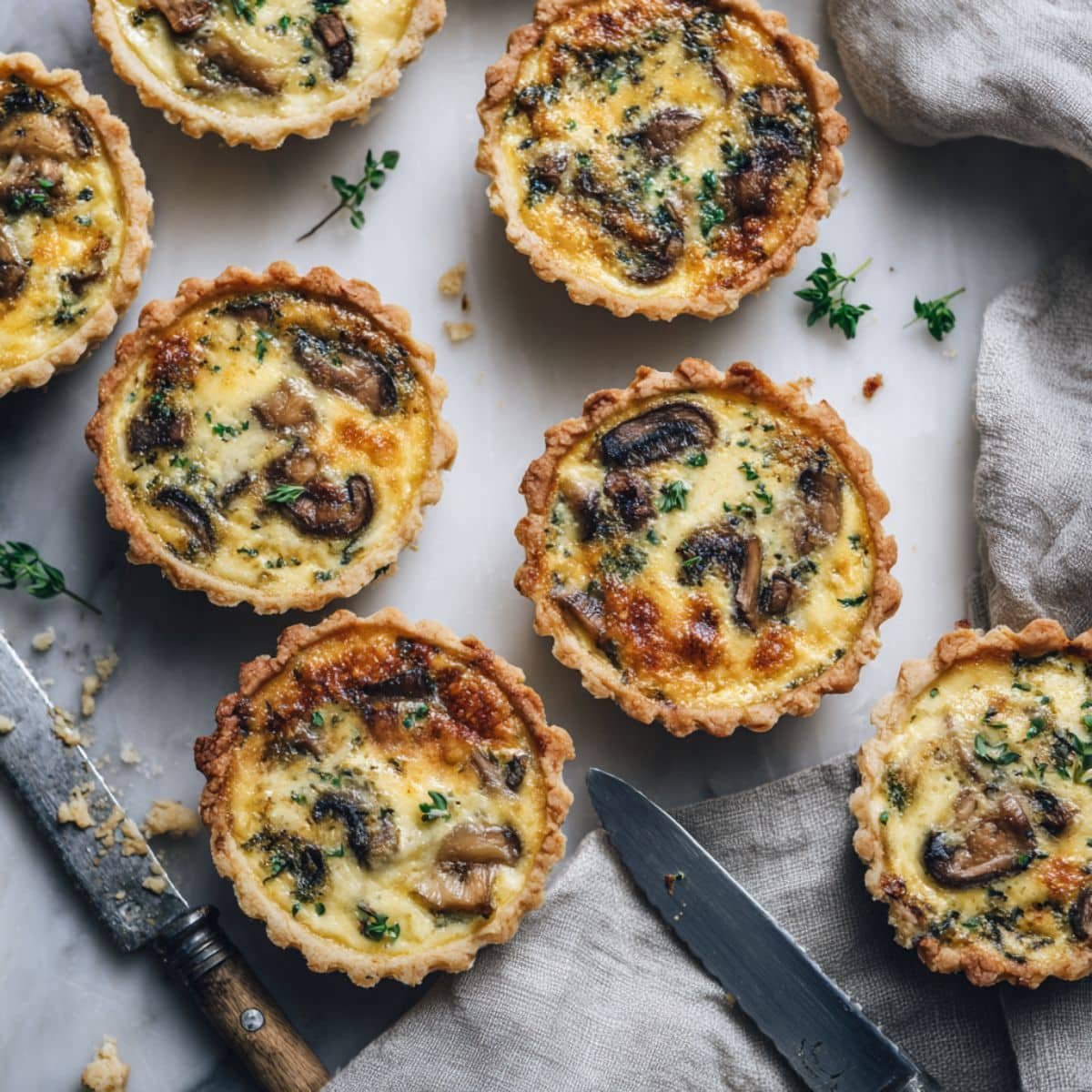 Homemade mini mushroom quiches cooling on a white kitchen table